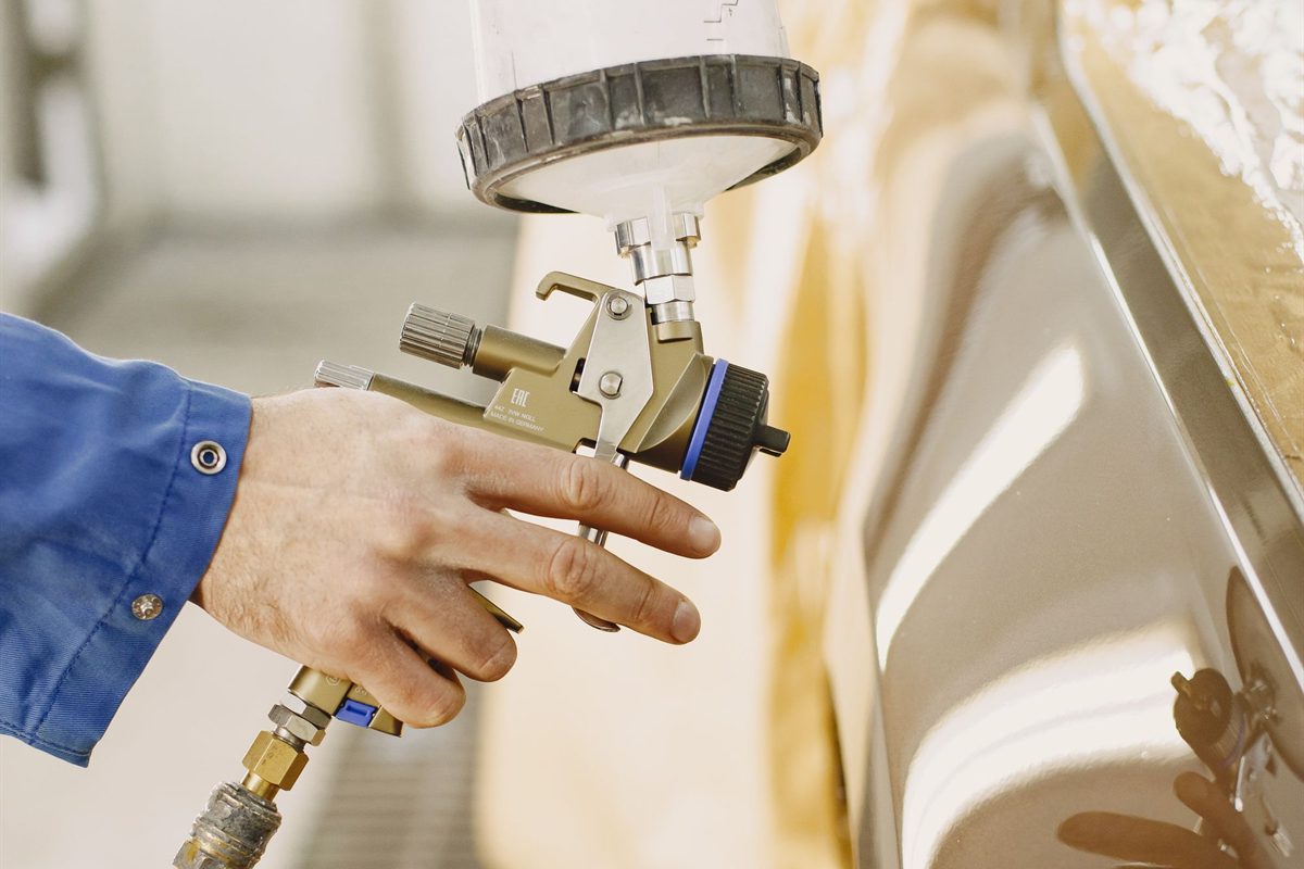 Spray gun laying paint onto a prepared panel