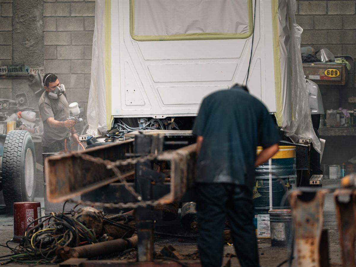 Spray painter in protective gear refinishing a car panel